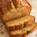 Homemade gluten-free zucchini bread with a golden crust, moist crumb, and visible flecks of zucchini, sliced thick for a rustic.