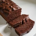 chocolate pound cake topped with shiny chocolate glaze, sliced to show its rich and moist interior