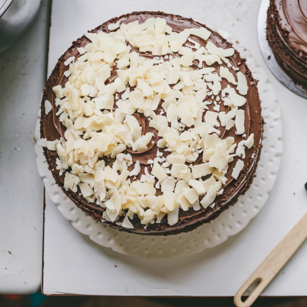 Assembled Mounds cake with coconut filling being spread between chocolate layers.