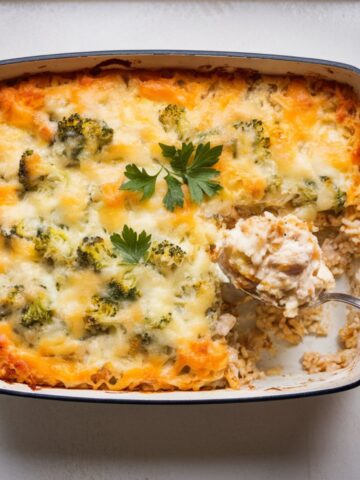 Cheesy chicken broccoli rice casserole in a white baking dish on a white counter