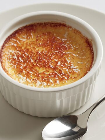 Homemade crab brulee served on a ramekin on a white plate.