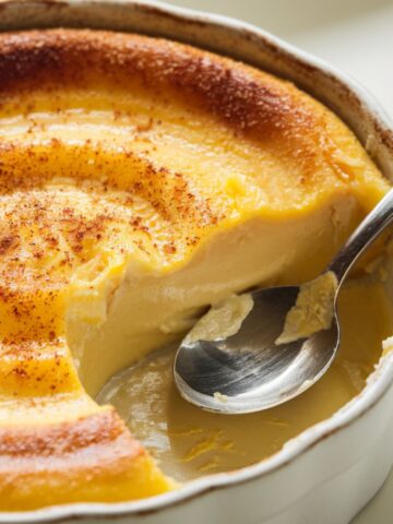 Close-up of creamy Amish baked custard with a golden top, a spoon revealing its silky texture.