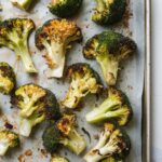 Golden-brown roasted broccoli with crispy edges on a parchment-lined baking sheet.