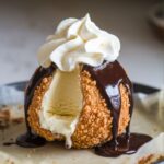 Close-up of homemade Air Fryer Fried Ice Cream with a crispy coating, topped with chocolate sauce and whipped cream.