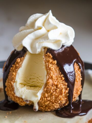 Close-up of homemade Air Fryer Fried Ice Cream with a crispy coating, topped with chocolate sauce and whipped cream.