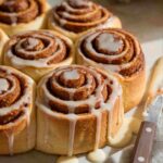 A fresh batch of golden-brown homemade cinnamon rolls with cream cheese frosting.