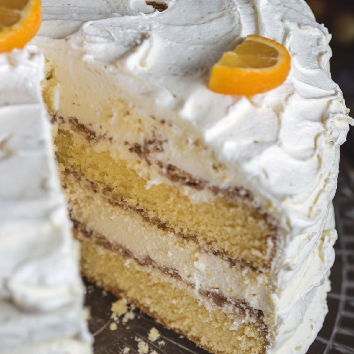 A homemade Pig Pickin Cake with fluffy whipped frosting and moist yellow cake layers, garnished with mandarin orange slices.