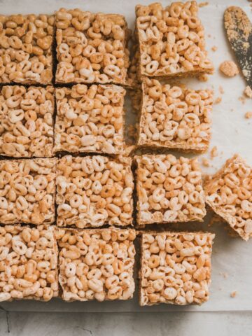 Original Rice Krispie treat recipe on a white kitchen counter, with a butter knife and crumbs beside them.