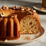 Homemade rum cake with a slice cut out, showing a moist, boozy interior. Perfect for celebrations and casual gatherings.