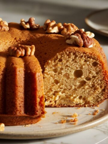 Homemade rum cake with a slice cut out, showing a moist, boozy interior. Perfect for celebrations and casual gatherings.