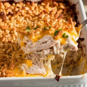 Golden, cheesy Ritz cracker chicken casserole with a crispy topping, served fresh from the oven. A spoon lifts a gooey, creamy portion with melted cheese stretching.