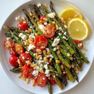 Rustic roasted asparagus salad with feta and tomatoes on a white kitchen counter. Fresh, spring-inspired and served on a casual platter.