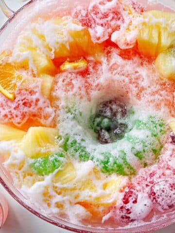 Fruit-filled ice ring in sherbet punch with fizzing soda. Includes pineapple, berries, orange slices, and rainbow sherbet.