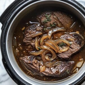 Chuck roast and onions in slow cooker ready to cook. This step starts the low-and-slow transformation.