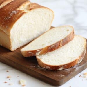 Homemade, soft sourdough sandwich bread sliced on a wooden board, flour-dusted crust and airy crumb.
