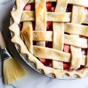 Lattice strips being laid over strawberry rhubarb filling, rustic and homemade.