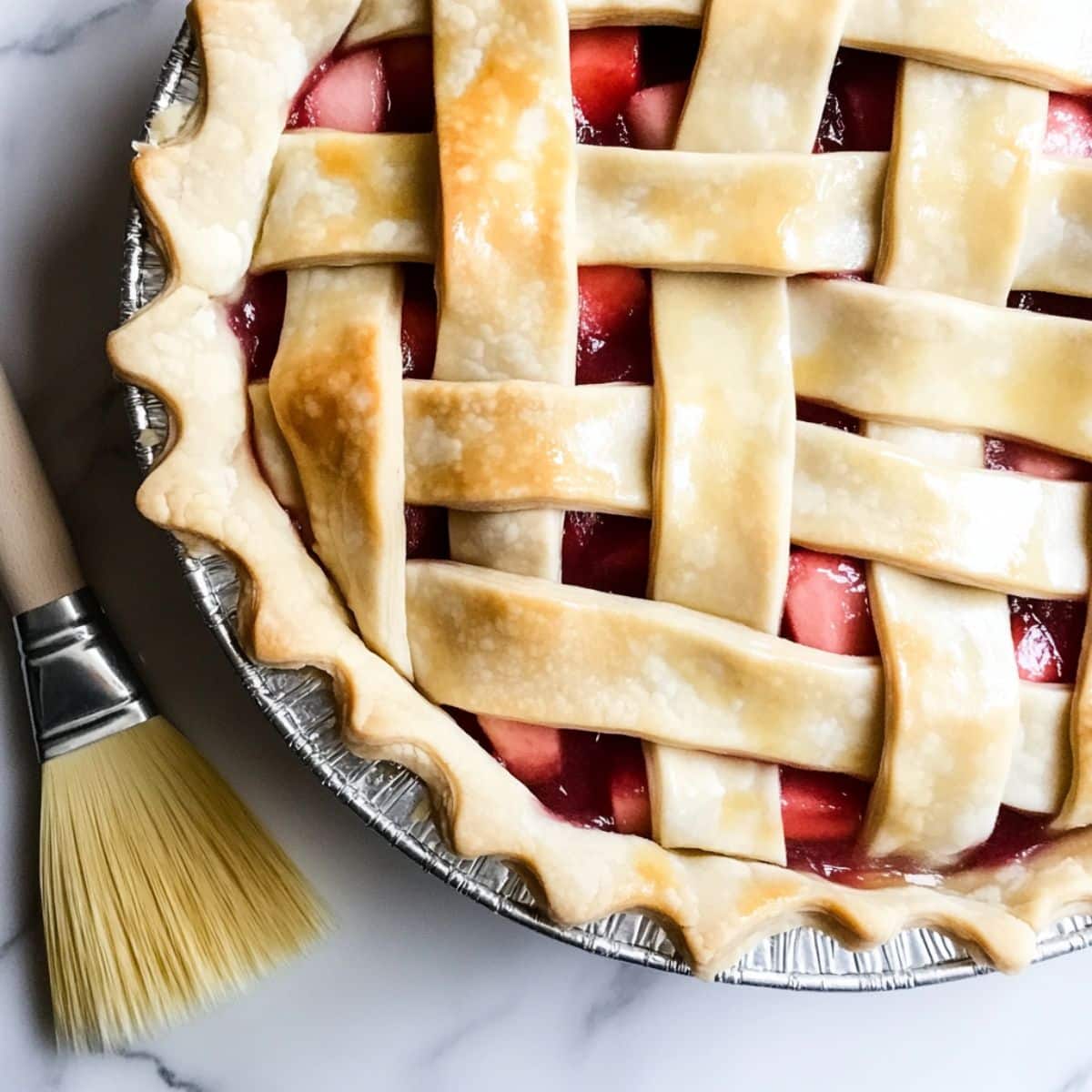 Lattice strips being laid over strawberry rhubarb filling, rustic and homemade.