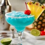 Bright blue Hawaiian margarita in salted glass, garnished with tropical fruit.