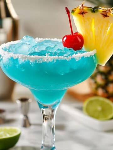 Bright blue Hawaiian margarita in salted glass, garnished with tropical fruit.