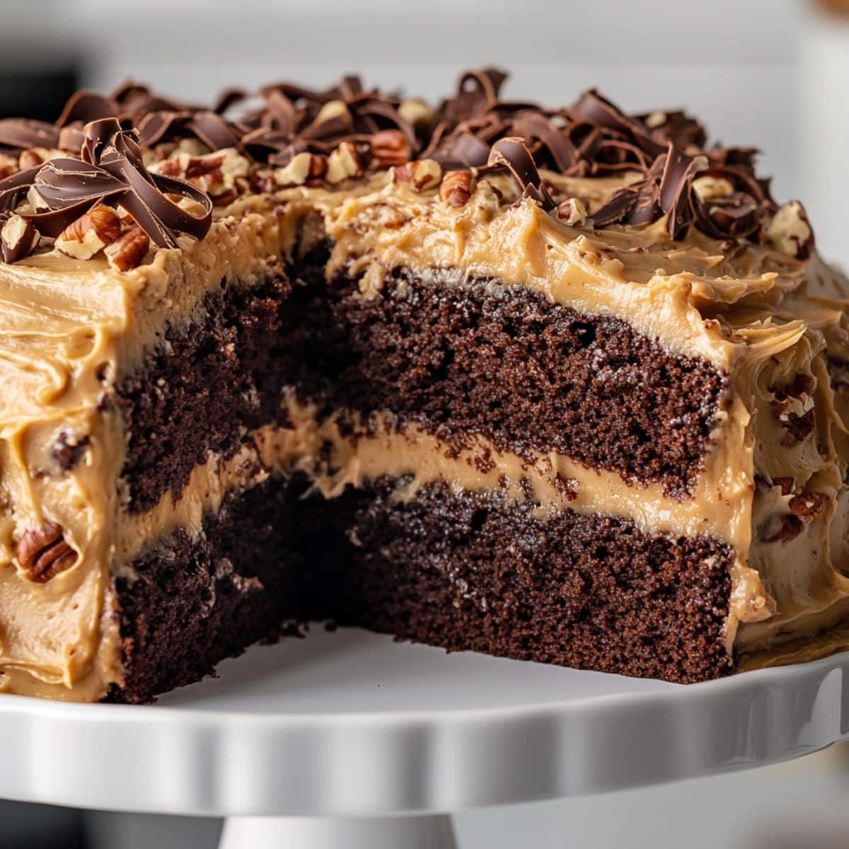 Final German chocolate cake assembly with coconut frosting, chocolate curls, and pecans on top.