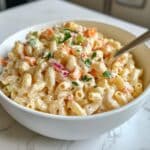 Creamy Hawaiian macaroni salad with elbow pasta, mayo dressing, red onion, carrots, and parsley garnish.