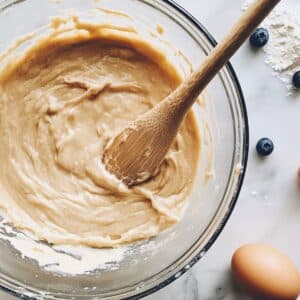 Thick pancake batter being mixed in a glass bowl.