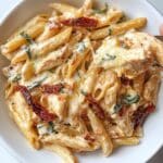 Creamy Marry Me Chicken Pasta with penne, sun-dried tomatoes, basil, and melted mozzarella. Rich, cheesy, and homemade on a white plate.
