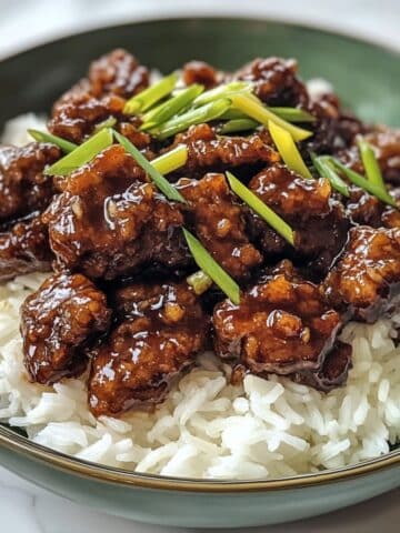 Overhead view of homemade Mongolian beef with rice on a white counter. Glossy sauce and crispy beef pieces give a takeout-style look at home.