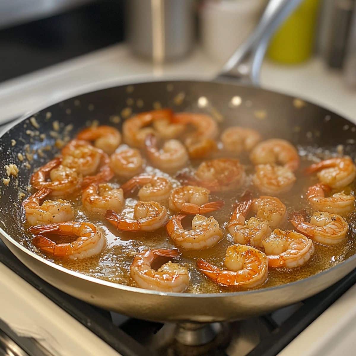 Shrimp searing in butter until pink and golden. Real stovetop shot for creamy shrimp pasta step.