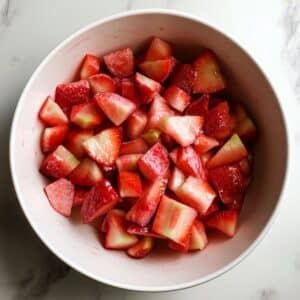 Bowl of fresh strawberries and rhubarb tossed with sugar and cornstarch for a strawberry rhubarb pie filling.