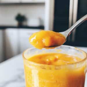 Tasting mango margarita mix from blender to check sweetness and slush texture before serving.