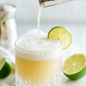 Tequila sour strained into rocks glass with foam rising.