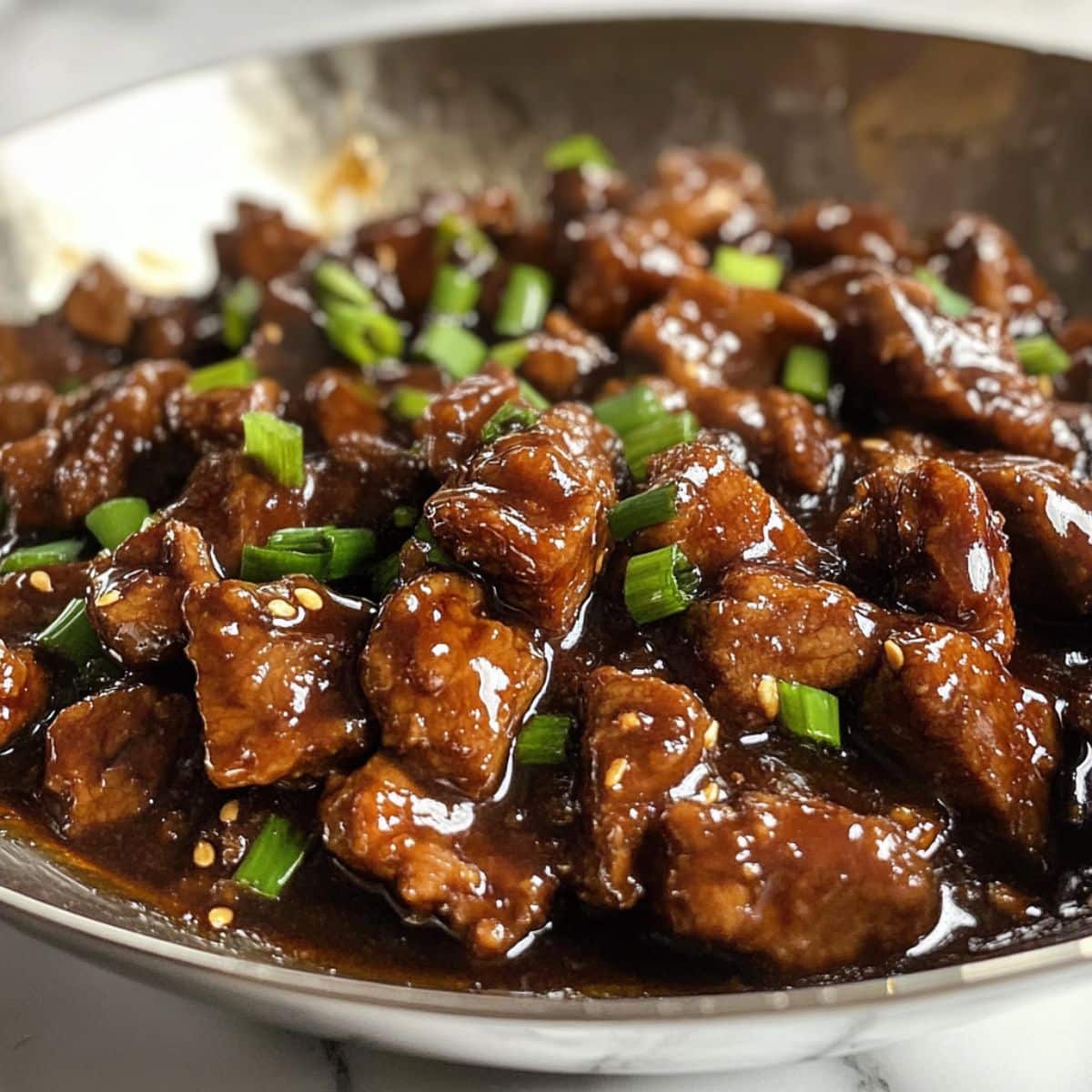 Crispy beef glazed in sweet-savory sauce with scallions. Final step before serving this homemade Mongolian classic.