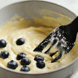 Blueberries being gently folded into pancake batter to prevent sinking.