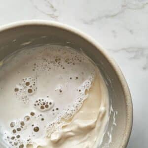 Mixing mayo, vinegar, and sugar into a smooth base dressing. Homemade prep step for creamy Hawaiian macaroni salad.