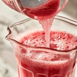 Strained watermelon juice poured into glass pitcher with light froth. Fresh, smooth, and ready to chill.