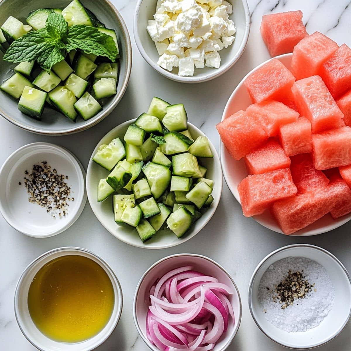 watermelon cucumber salad ingredients laid out on a white counter in a casual home kitchen setting.