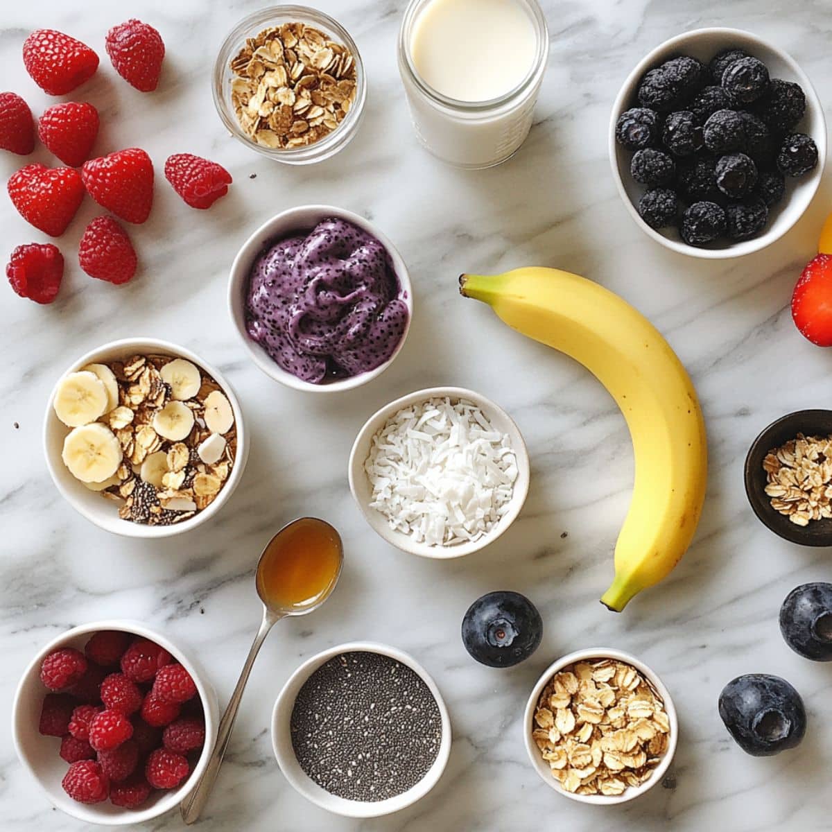 All acai bowl ingredients laid out on a white kitchen counter, from frozen acai to fresh fruit and toppings.