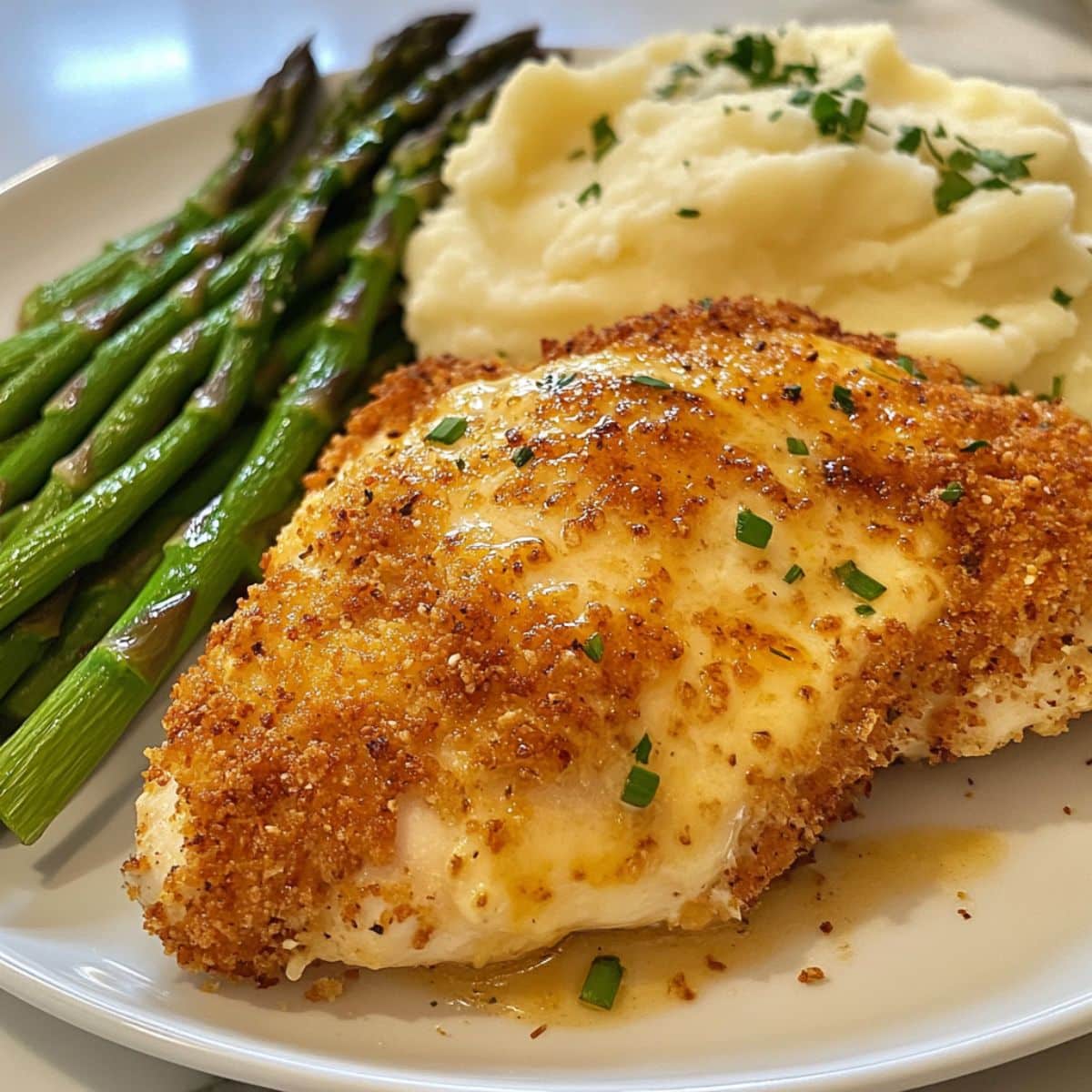 Homemade Longhorn Parmesan Crusted Chicken with golden cheese topping served with asparagus and mashed potatoes.