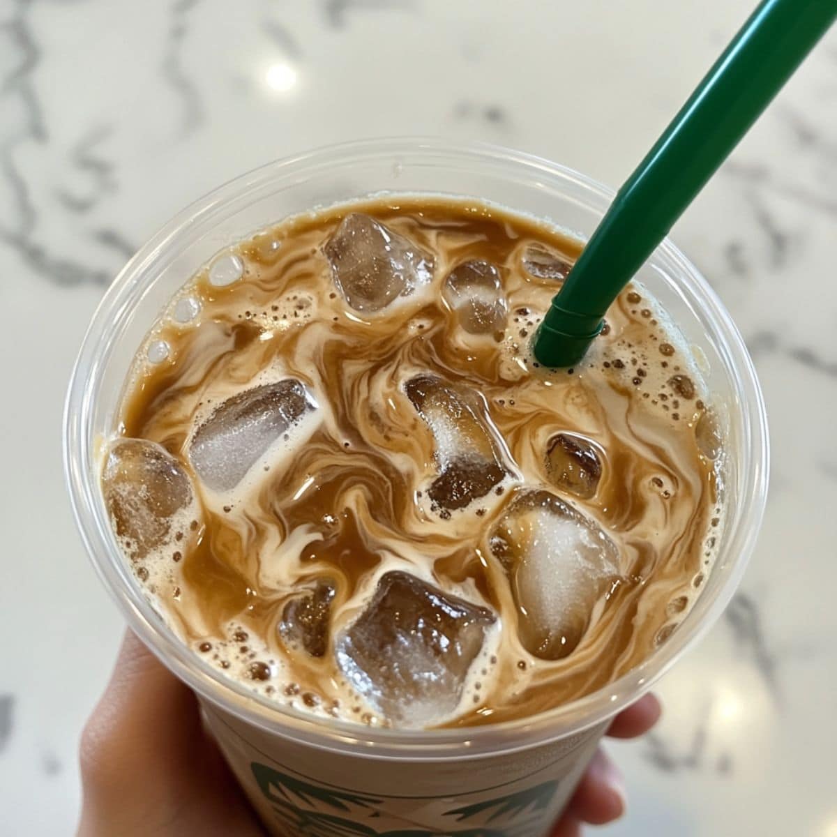 Stirred homemade iced coffee with visible coffee cubes, ready to enjoy on a kitchen counter.