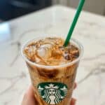 Starbucks iced coffee in a plastic cup with creamy swirls and ice cubes. A homemade copycat drink that looks refreshingly café-ready.