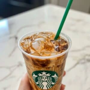 Starbucks iced coffee in a plastic cup with creamy swirls and ice cubes. A homemade copycat drink that looks refreshingly café-ready.