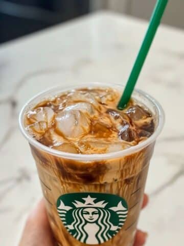 Starbucks iced coffee in a plastic cup with creamy swirls and ice cubes. A homemade copycat drink that looks refreshingly café-ready.