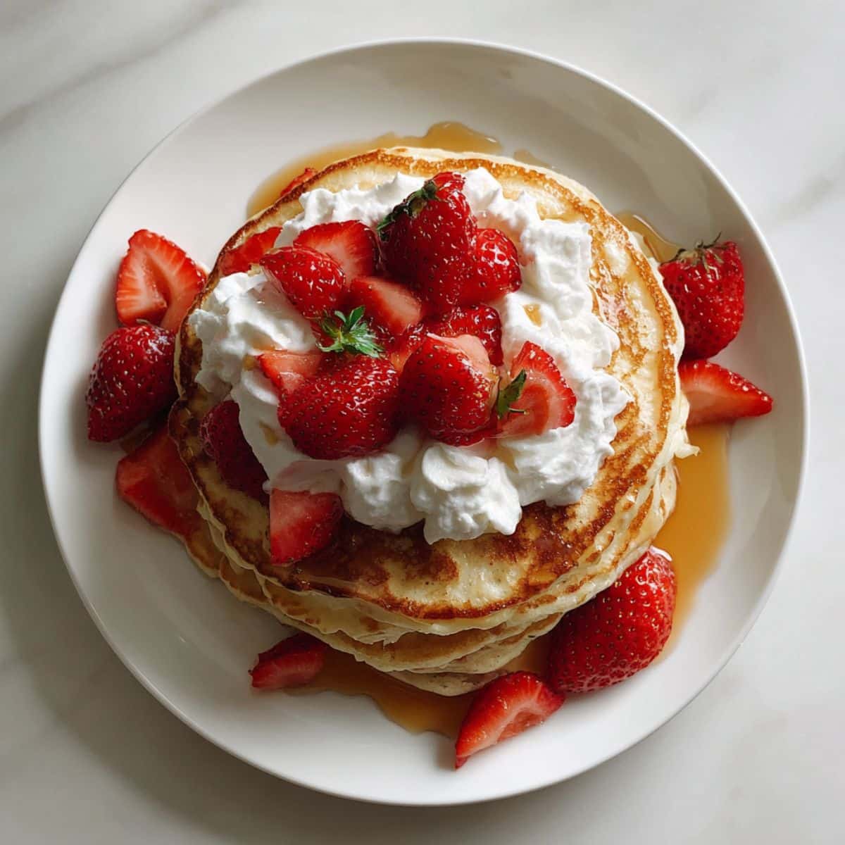 Fluffy strawberry pancakes topped with fresh berries and syrup.