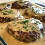 Creamy amish hamburger steak bake casserole with juicy beef patties smothered in thick white gravy. Real homemade look from an overhead kitchen shot.