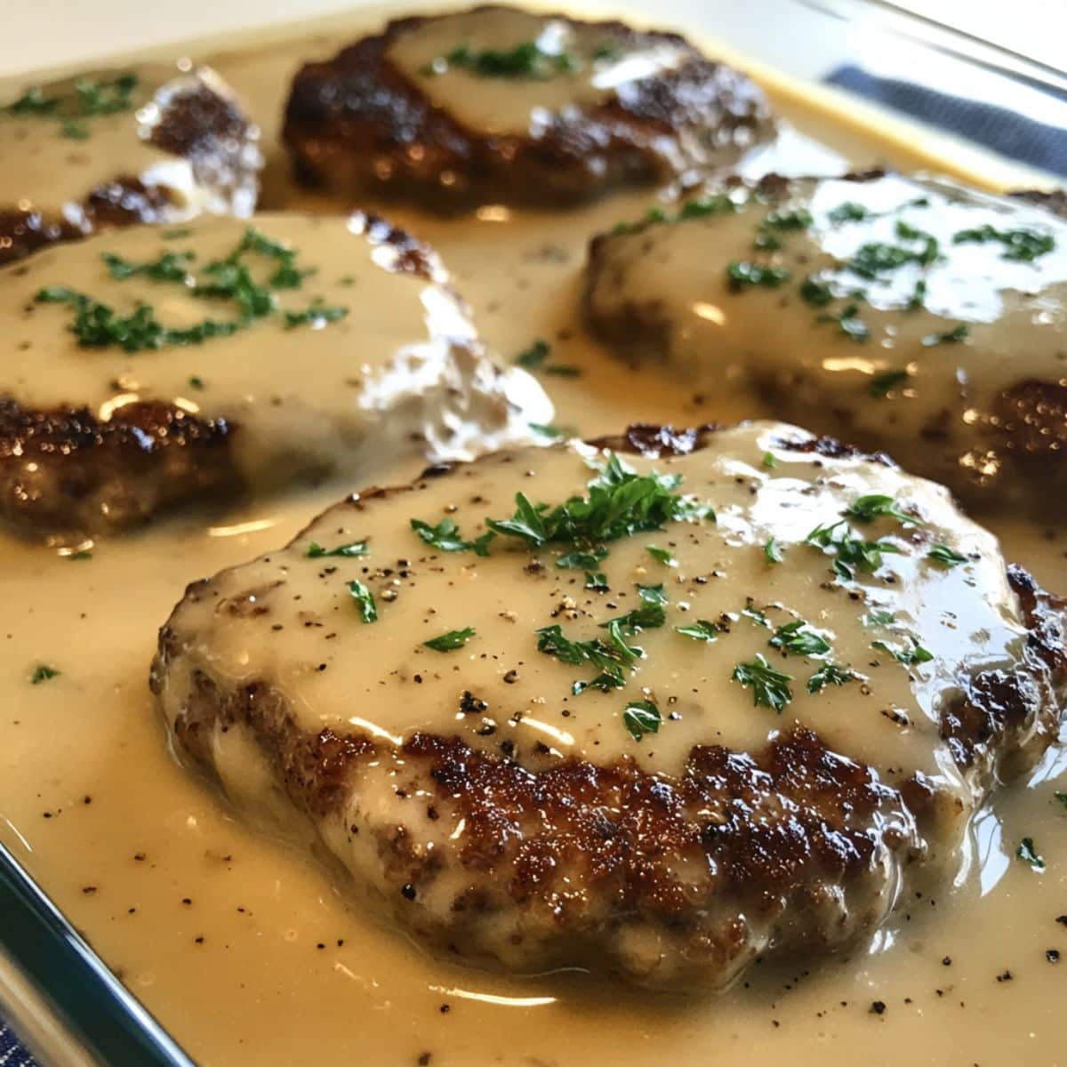 Creamy amish hamburger steak bake casserole with juicy beef patties smothered in thick white gravy. Real homemade look from an overhead kitchen shot.