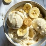 Homemade banana pudding ice cream with Nilla wafers and bananas on white kitchen counter. Classic Southern frozen dessert in bowl.