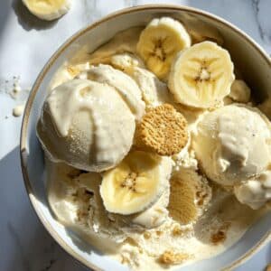 Homemade banana pudding ice cream with Nilla wafers and bananas on white kitchen counter. Classic Southern frozen dessert in bowl.