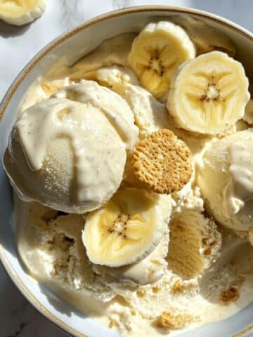 Homemade banana pudding ice cream with Nilla wafers and bananas on white kitchen counter. Classic Southern frozen dessert in bowl.