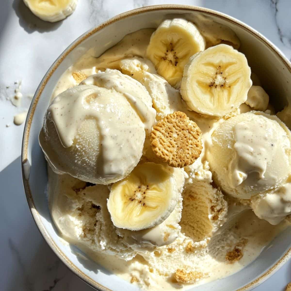 Homemade banana pudding ice cream with Nilla wafers and bananas on white kitchen counter. Classic Southern frozen dessert in bowl.